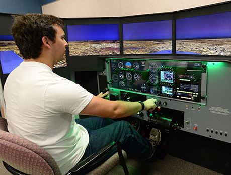Man in white shirt practices flying plane on flight simulation technology