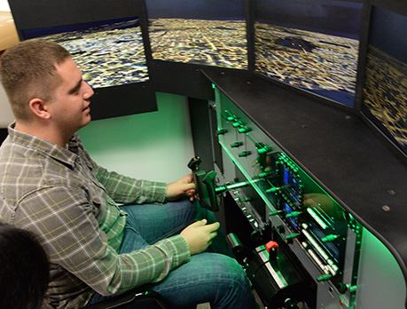  Man in grey plaid shirt practices flying plane on flight simulation technology