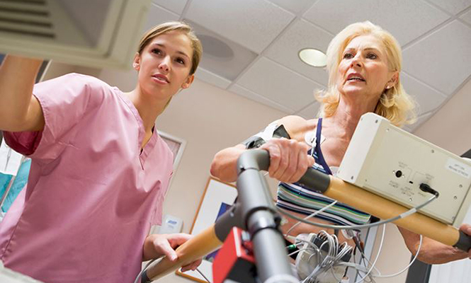 Electrocardiography technician reviews patient's results while patient walks on treadmill