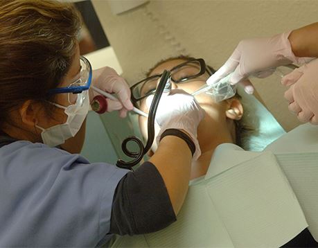 Dental assistant helps dentist clean patient's mouth