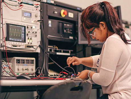 A woman connects the circuit board to the testing system