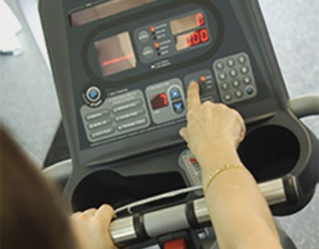 Female fitness client reviews exercise stats on treadmill