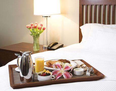 Tray of breakfast food on bed in hotel room
