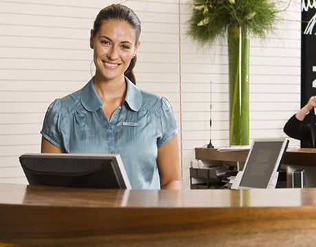 Female front desk manager in green shirt smiles