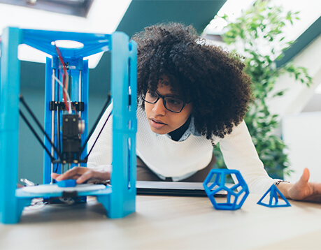 Female student looks on as 3D printer is in process