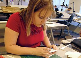 Female architect works on a design using paper and rulers