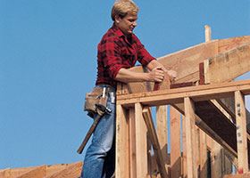 Man in plaid shirt stands on a roof frame