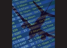 A monitor showing airport arrival and departure with a reflection of an airplane