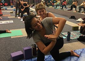 A yoga instructor corrects a student's pose during class