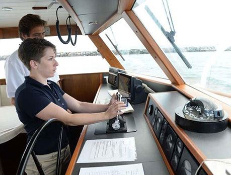 female professional mariner steering a boat