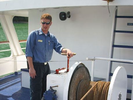 A male professional mariner pulls up the ship anchor