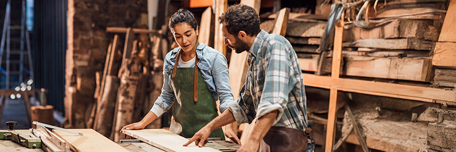 Two craftsmen collaborating on a woodworking project in a workshop.
