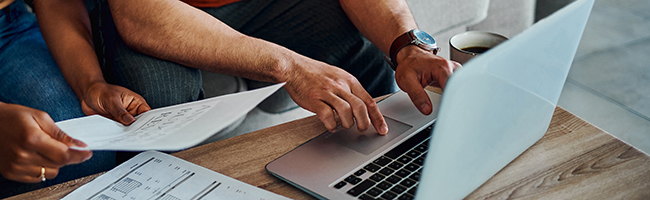 Two people collaborating while using a laptop and focused on a document.