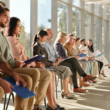 People seating in a row in waiting area.
