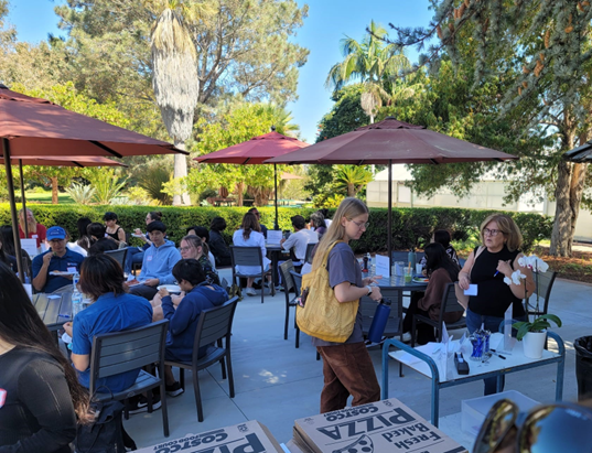 students sitting around tables in a garden engaging in discussion