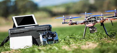 Drone and remote controller set on a grassy field.
