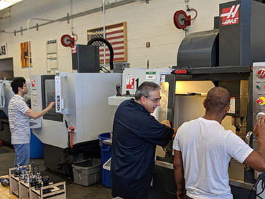 Al cervantes working with students at the Haas VF 1 CNC mill.