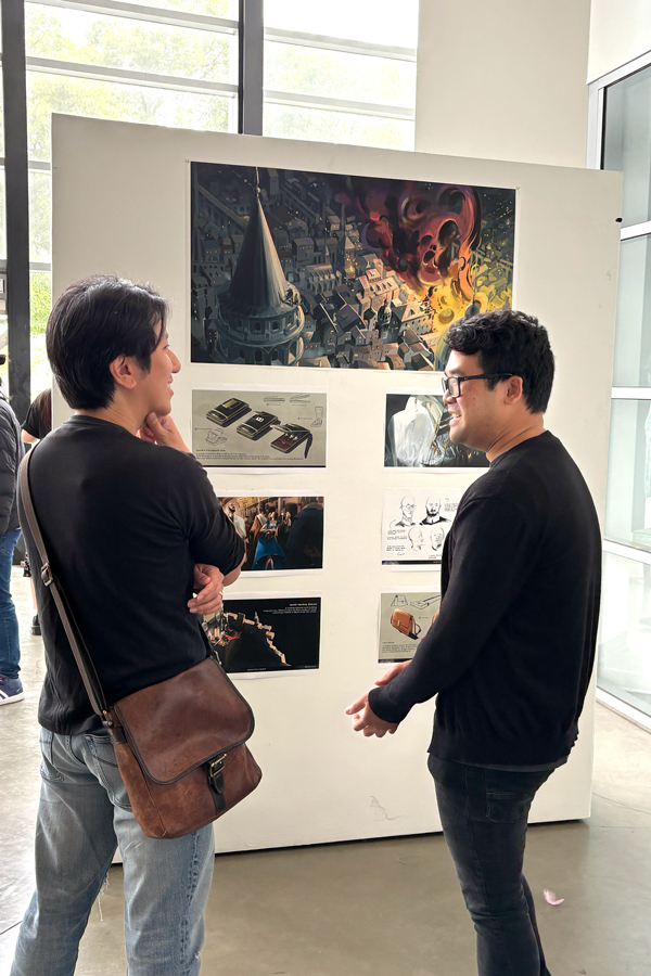 Two individuals engaged in conversation in front of an art display featuring a dramatic illustration of a cityscape with fiery elements.