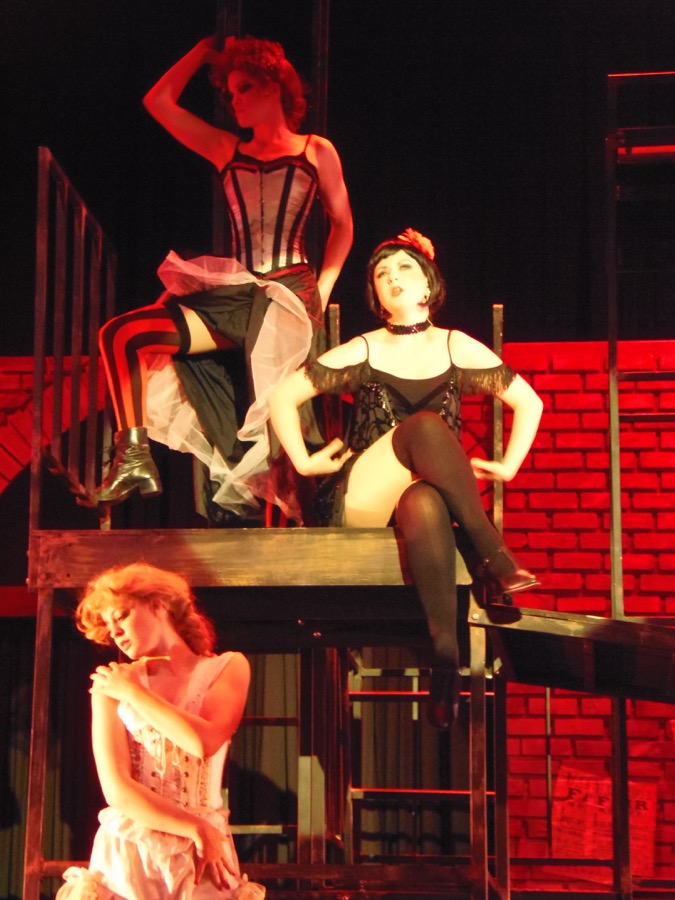 3 women sitting and standing on stage