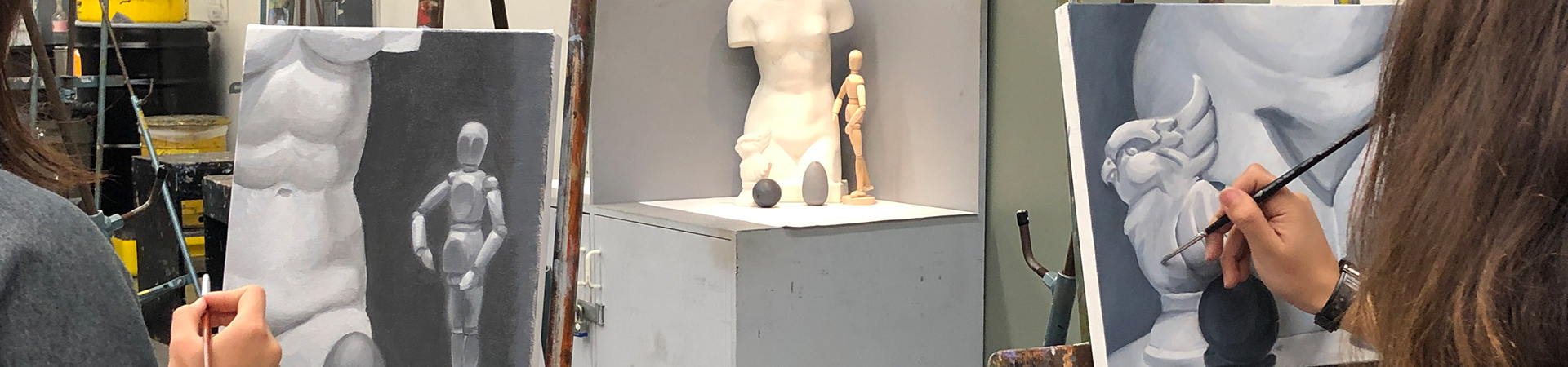 students painting on a canvas of a statue and a wooden figure.