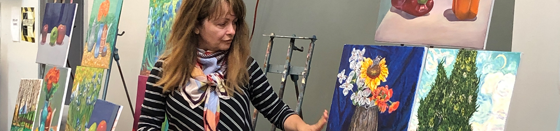 Arts faculty observing different paintings on easels