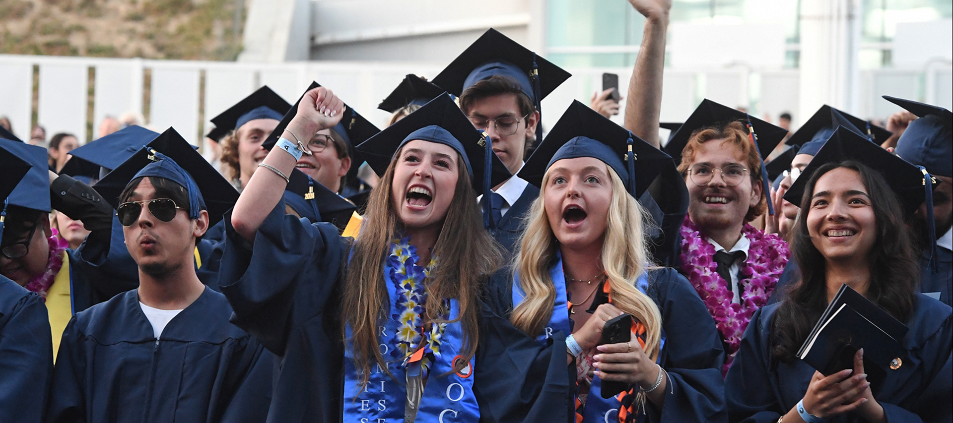 A group of graduates cheering at commencement.