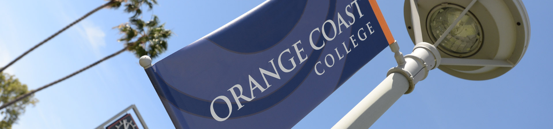Orange Coast College spirt banner hanging on a lamp post.