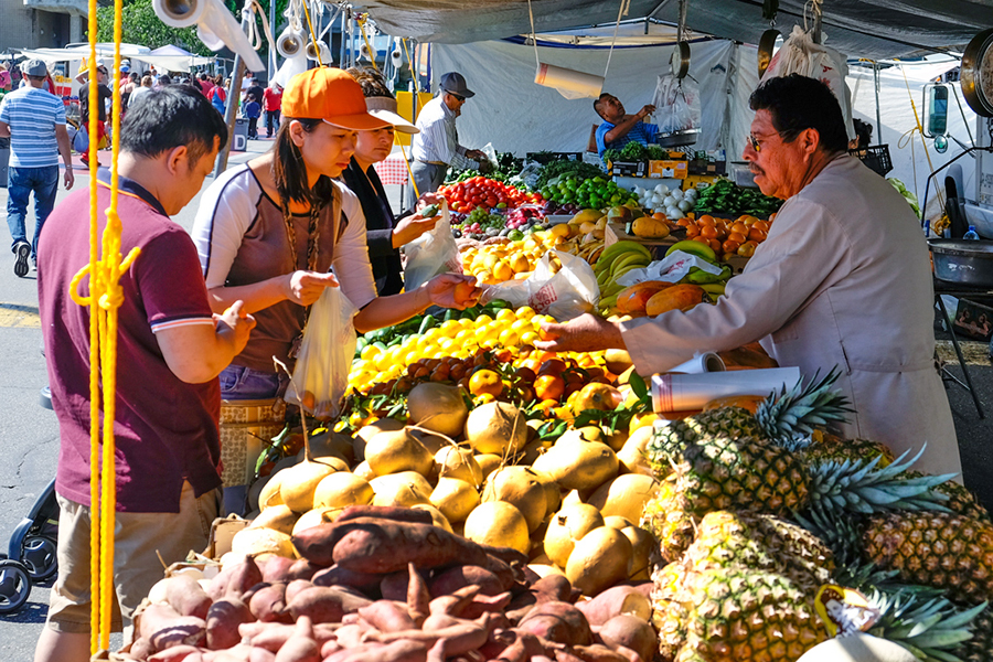 A vendor handing a fruit to a visitor.