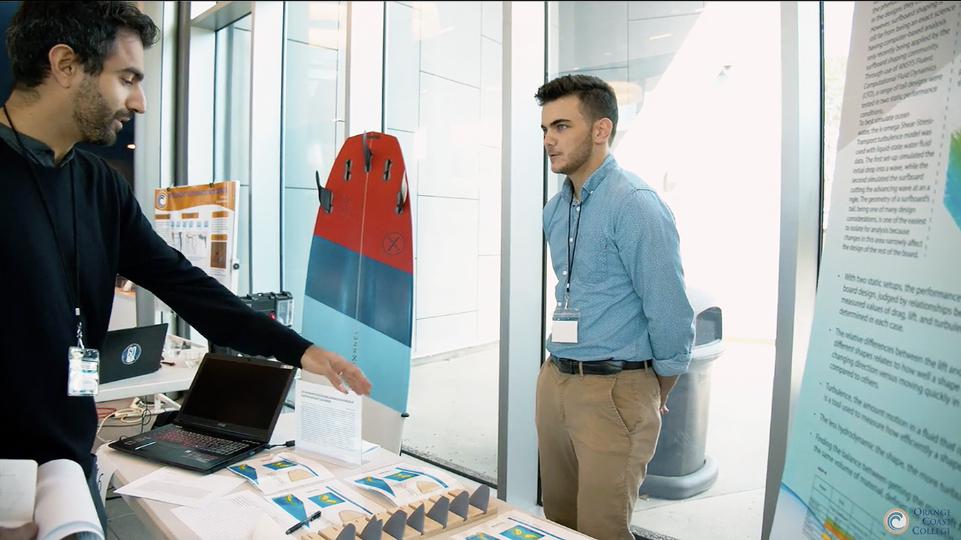 photo of bodhi edwards standing at table talking to someone about his project