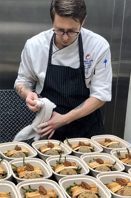 A volunteer prepping many packaged meals