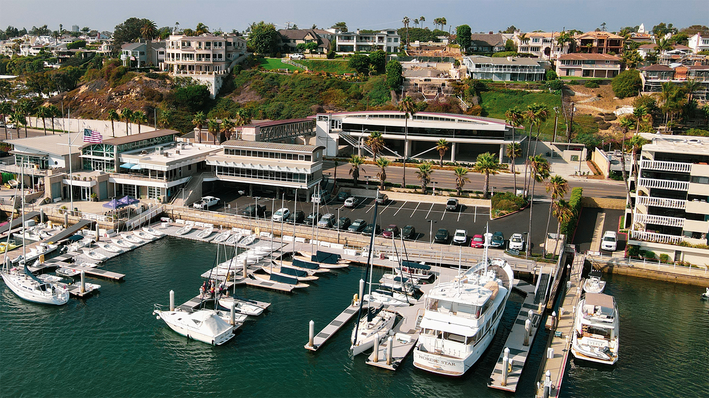 drone photo taken from high in the sky of of waterfront building with docks and sailboats 