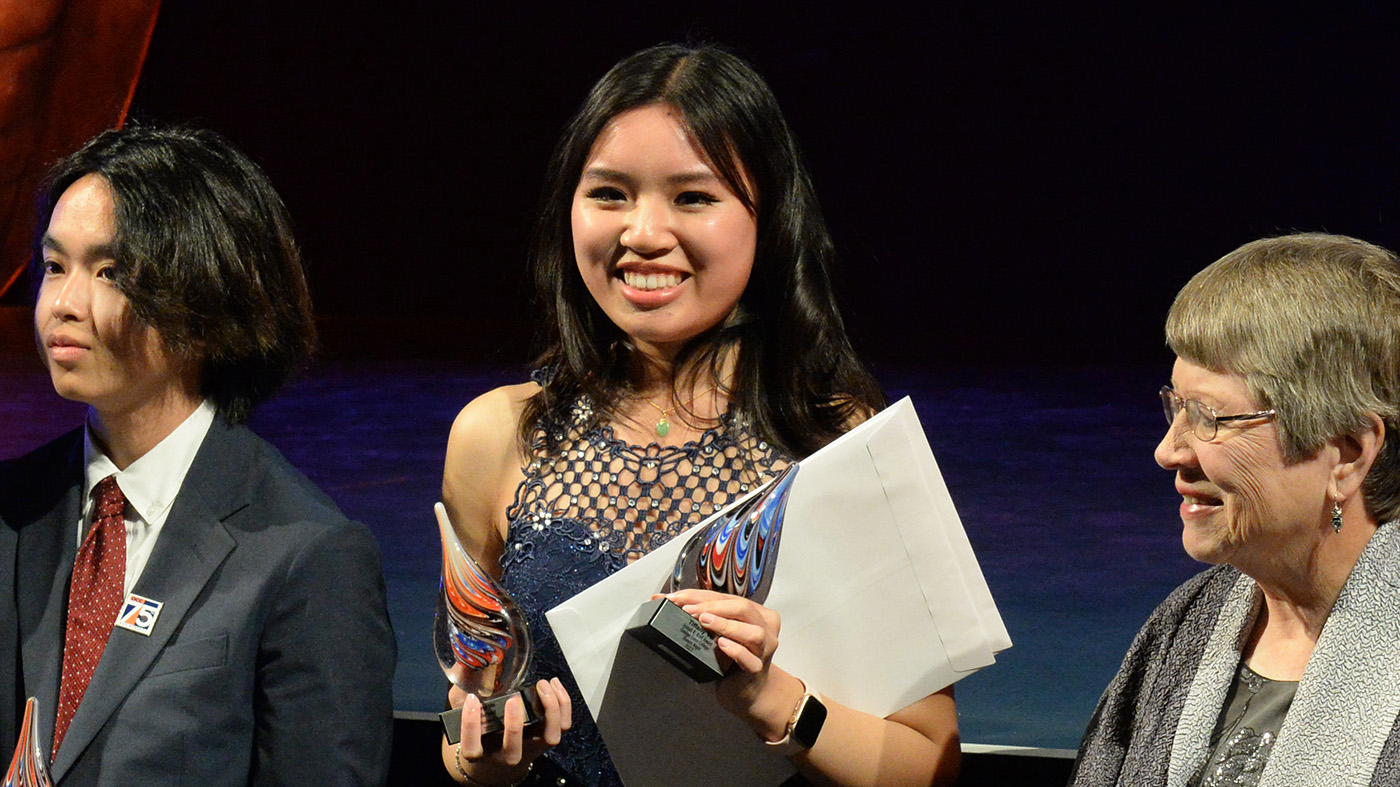 Three individuals on a stage at an awards ceremony
