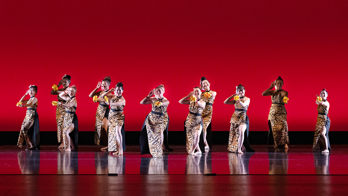 dances on stage with a red background behind them