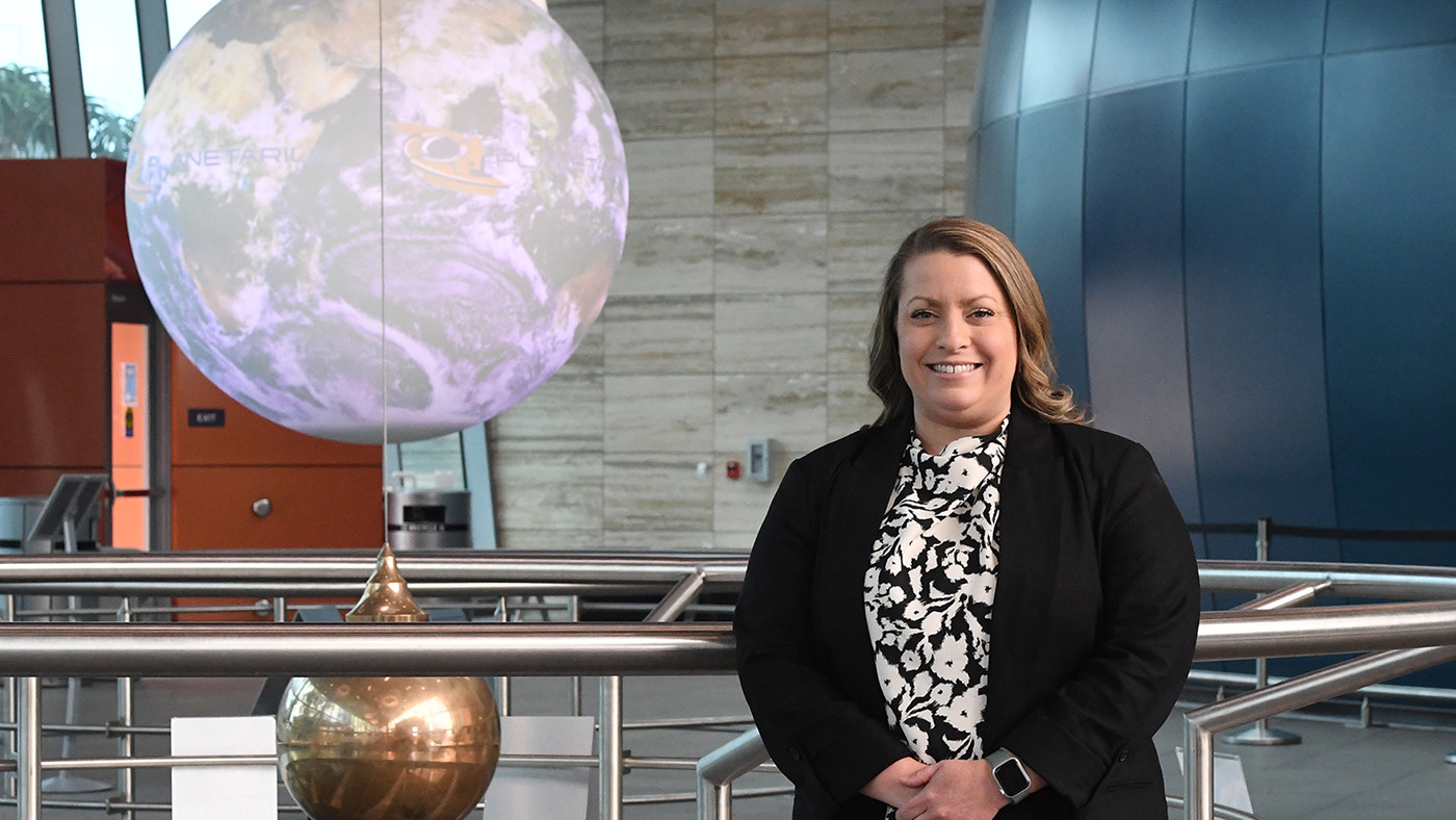 Hanging Earth sphere and pendulum on the left side and woman on the right side of the image
