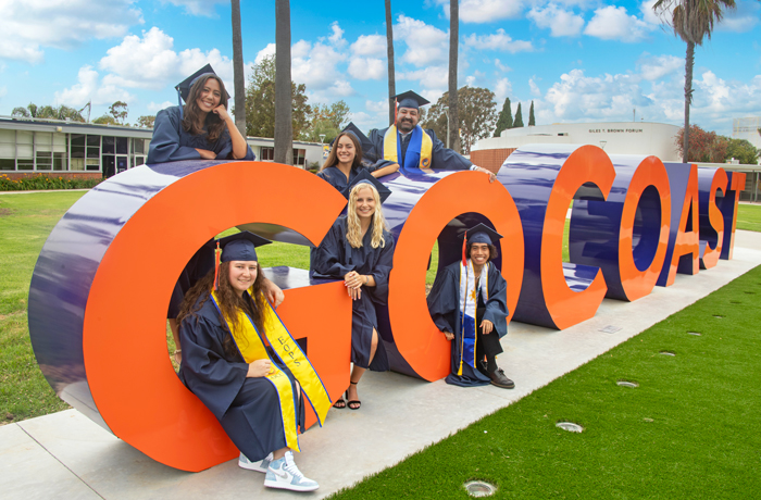 group of students hanging around the GO Coast monument letters