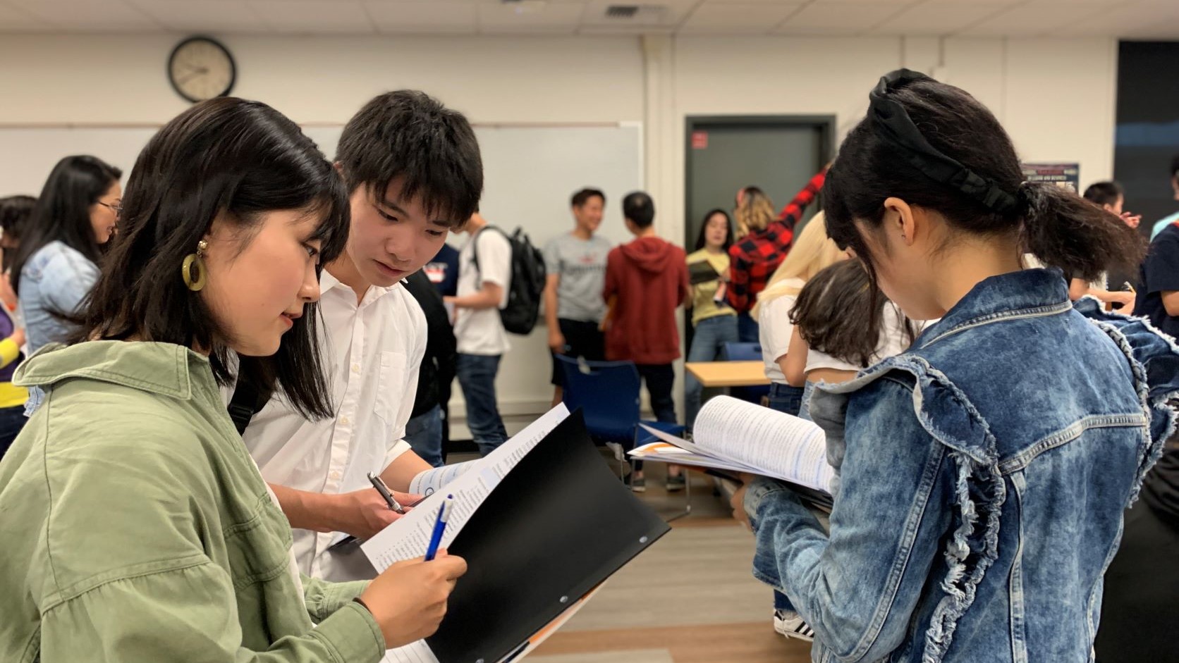 3 student facing each other with papers in hand