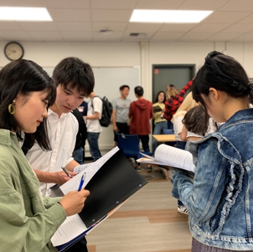 3 students facing each other with papers in hand