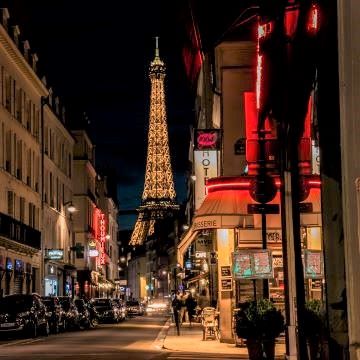 Eiffel Tower at night with street and cafe's in foreground