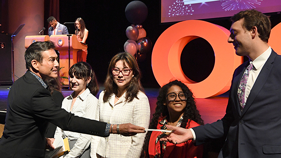 Donor handing out checks to a group of scholarship recipients at the ceremony.