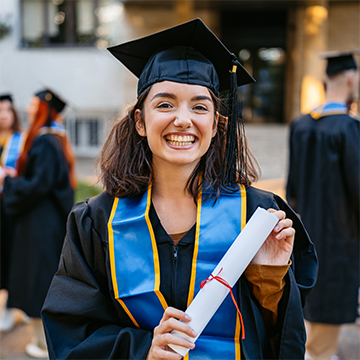A student in cap and gown holding a degree.