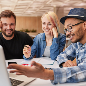 3 students working together at the table looking at a computer
