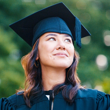 A student in cap and gown looking up.